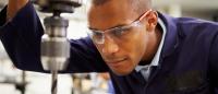 man using drill press and wearing protective eyewear